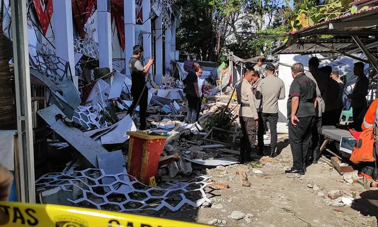 People inspects debris at the site of a damaged building following an earthquake in Manado, North Sulawesi province, Indonesia.