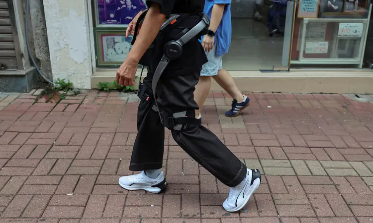 A resident of Wang Fuk Court, tries on a robotic exoskeleton ahead of her first visit home to retrieve belongings after a deadly fire last year, in Hong Kong, China.