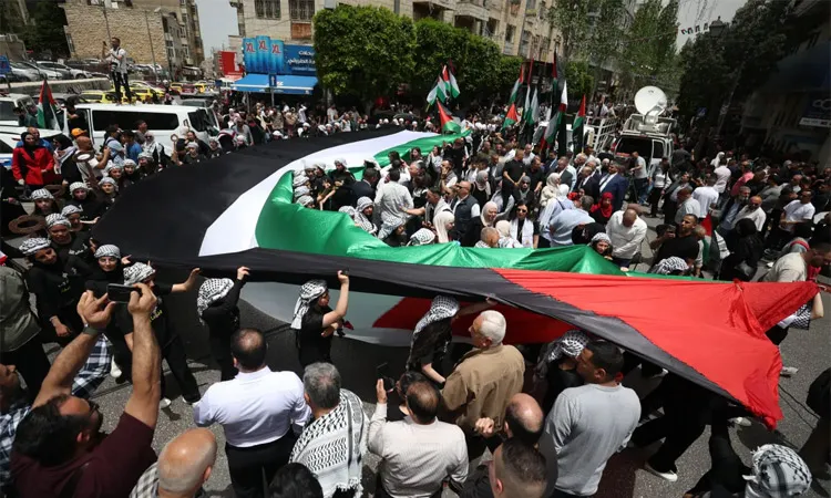Palestinians carry a giant flag and symbolic representations of keys to homes that people were forced to leave as they rally to mark the 78th anniversary of the Nakba, in Ramallah, in the Israeli-occupied West Bank.