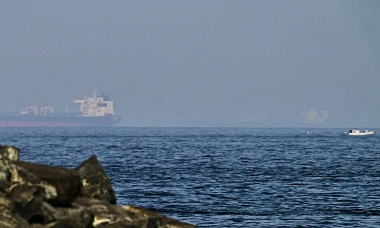 Cargo ships are seen at sea in the Gulf of Oman near the Strait of Hormuz, as viewed from a rocky shoreline near Khor Fakkan, United Arab Emirates.