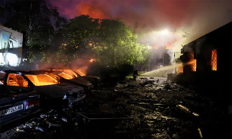 A firefighter works near burning cars at the site of an apartment building damaged during Russian missile strikes amid Russia’s attack on Ukraine in Kyiv, Ukraine.