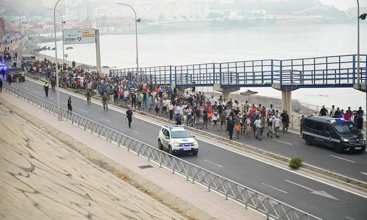Police officers and Spanish soldiers escort a big group of migrants to the border to take them out of Spain, after mass crossings of migrants on foot and by sea from Morocco into Spanish territory, in Ceuta, Spain.