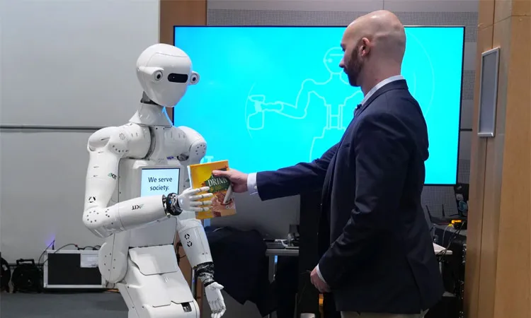 A man receives a box of chocolate powder drink from a robot during a demonstration of AI-based robotics in Europe .